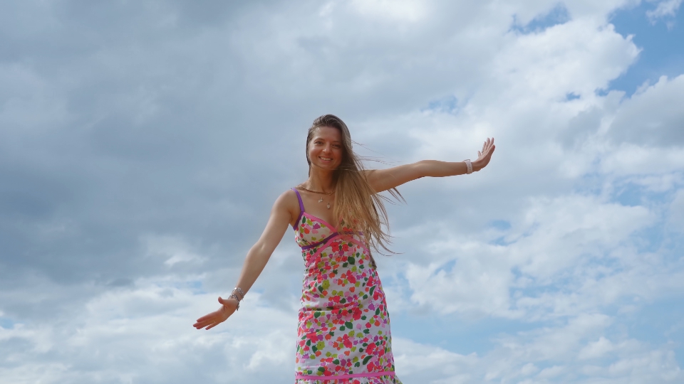 Young woman moves having fun in front of summer sky