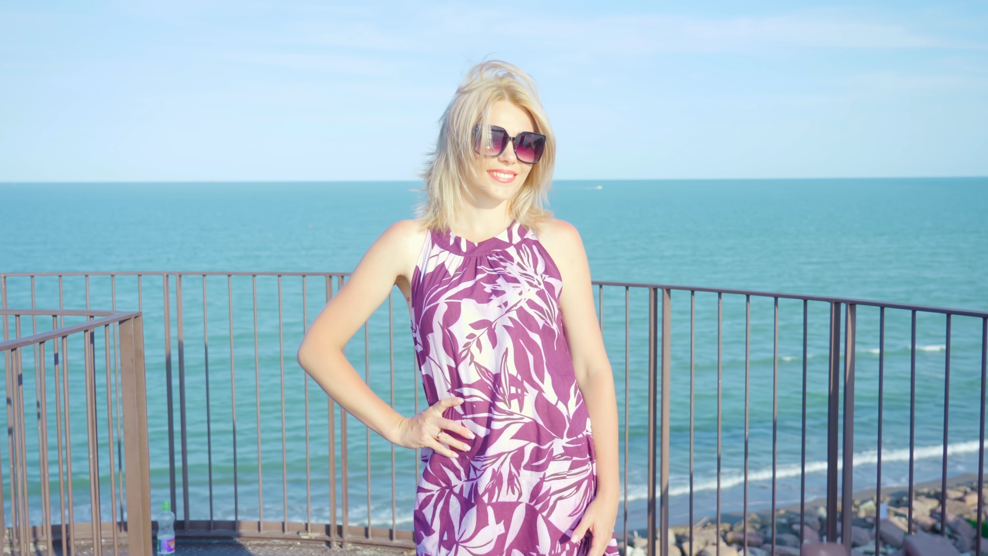 Blond young woman smiles in front of azure sea