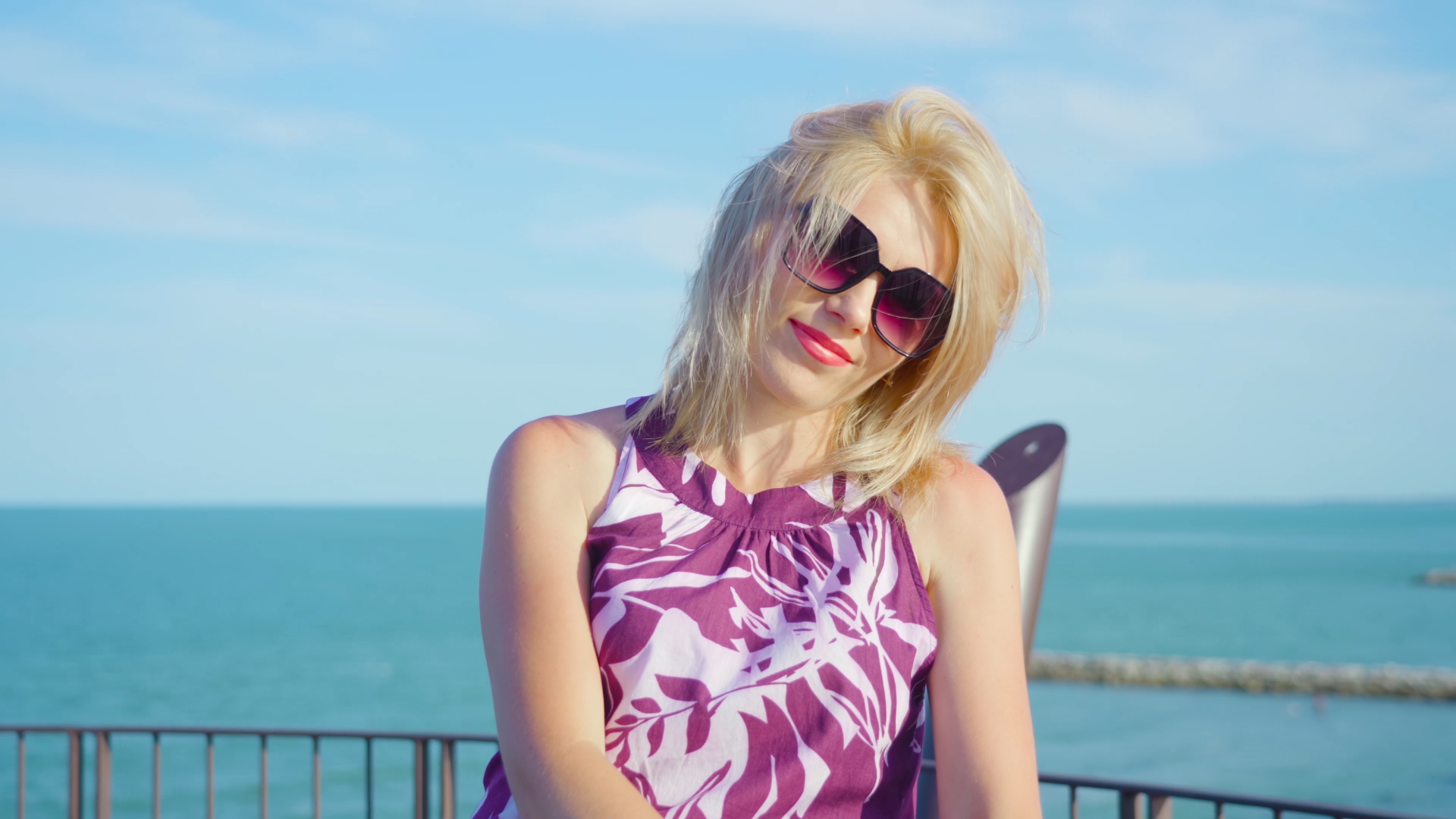 Blond woman sitting high up on tower smiles looking into camera