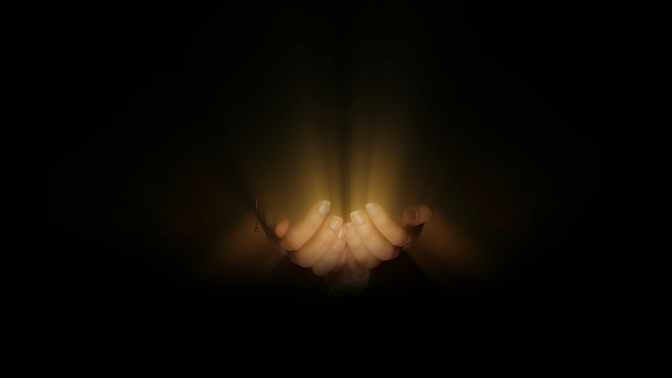 Raggi di luce compaiono nelle mani nello scuro