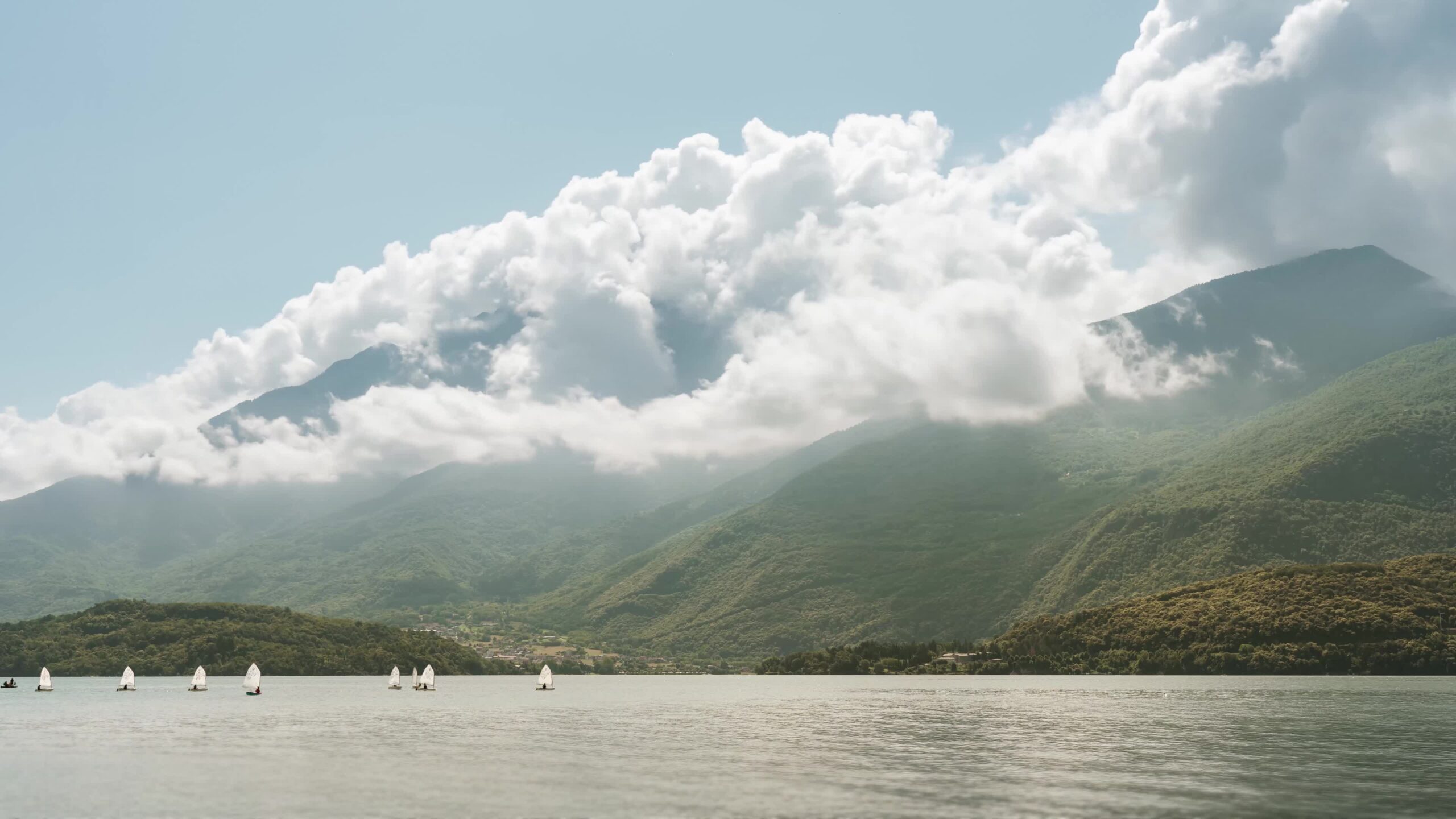 Timelapse dei monti tra nuvole bianche e barche a vela sul fiume