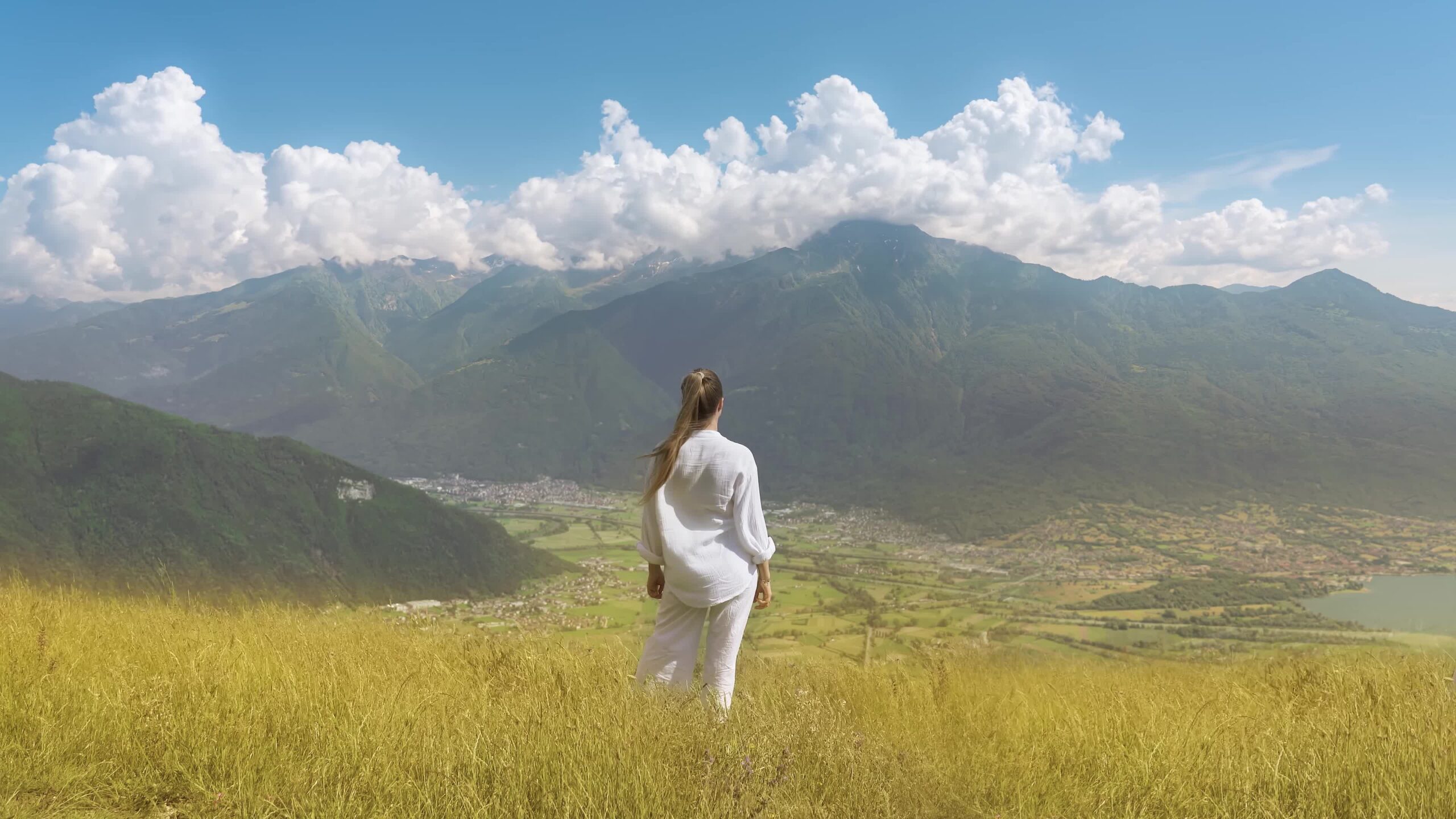 Woman observes in the wind beautiful relaxing landscape of green summer mountains
