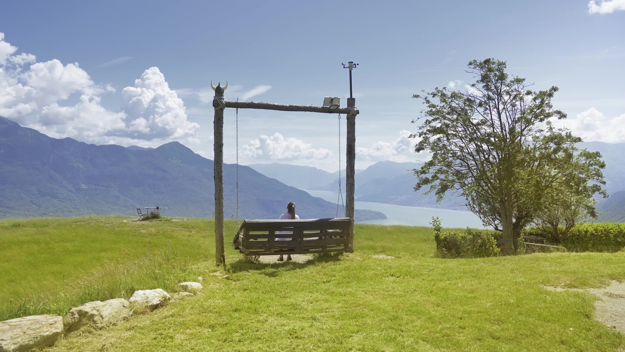 Woman relaxes on swing in front of mountains landscape at lake Como