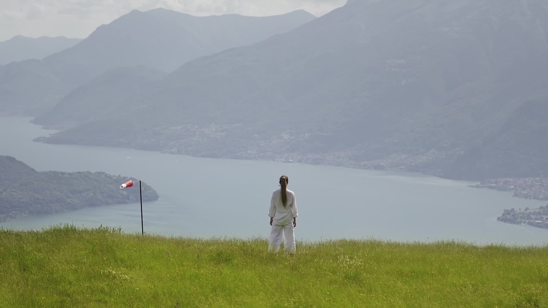 Donna ferma in piedi di spalle osserva lago tra montagne