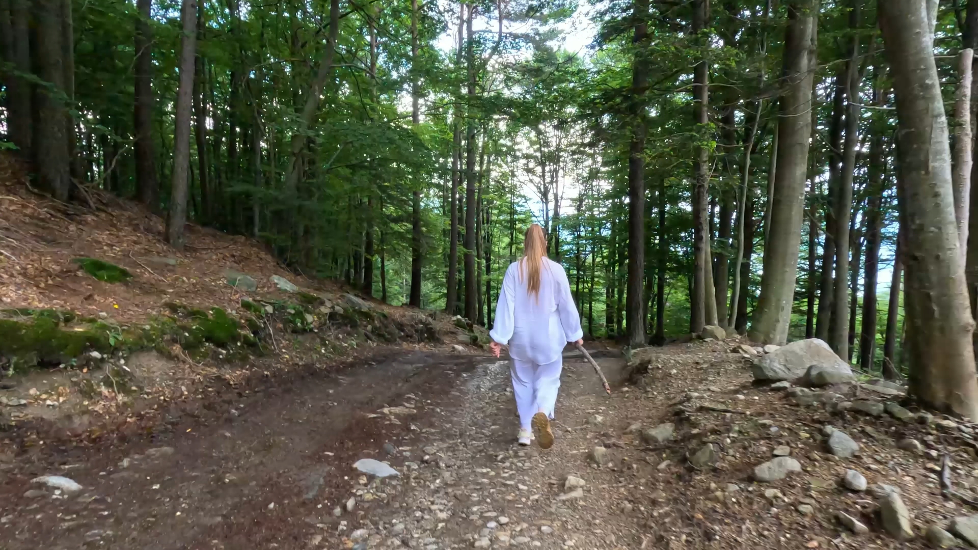 Donna vestita di bianco cammina velocemente nel bosco