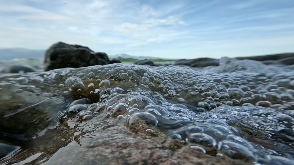 Riva del lago ricoperta di sassolini bagnata dall’acqua