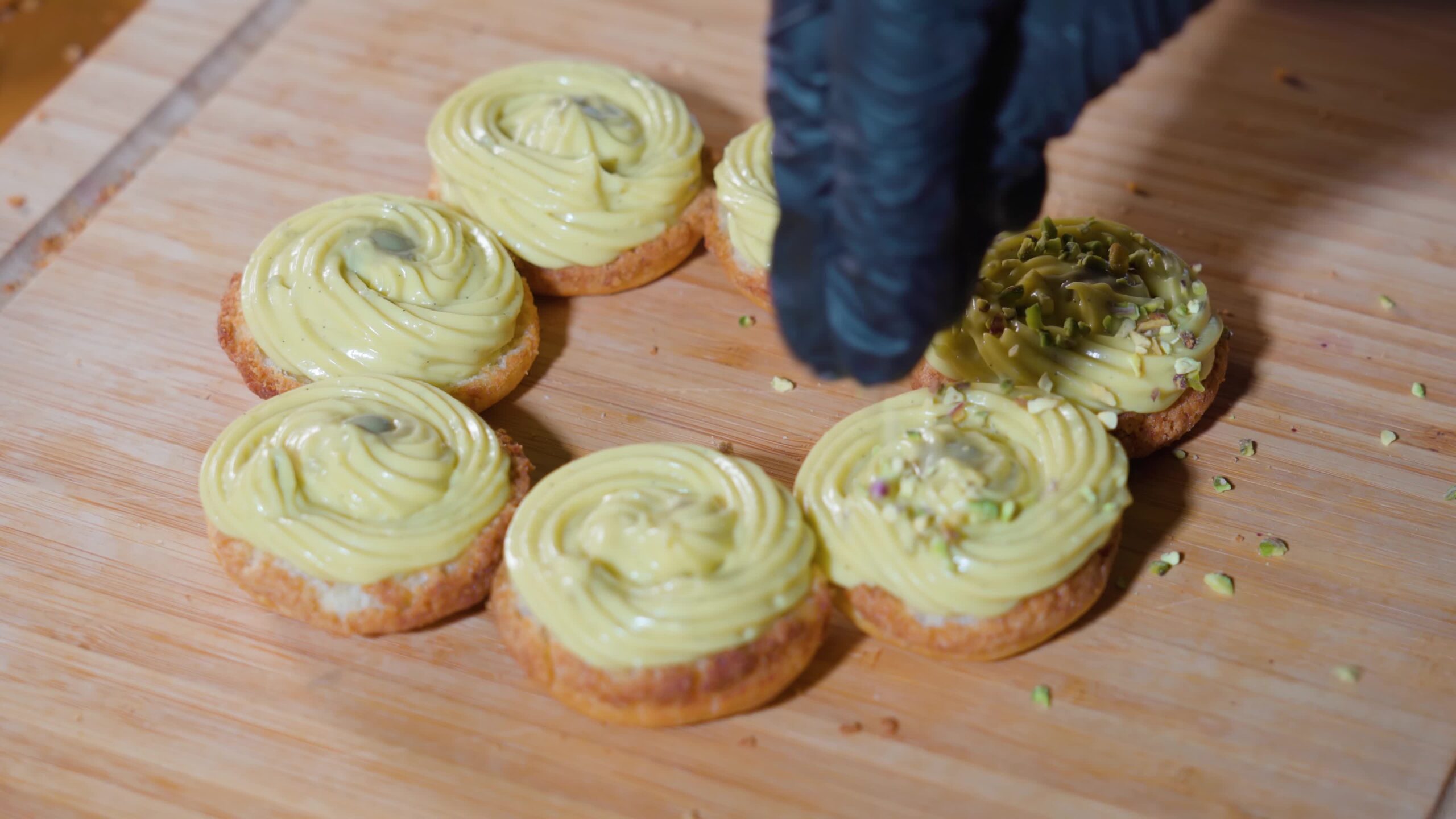 Small pieces of pistachio are placed on pastries with custard