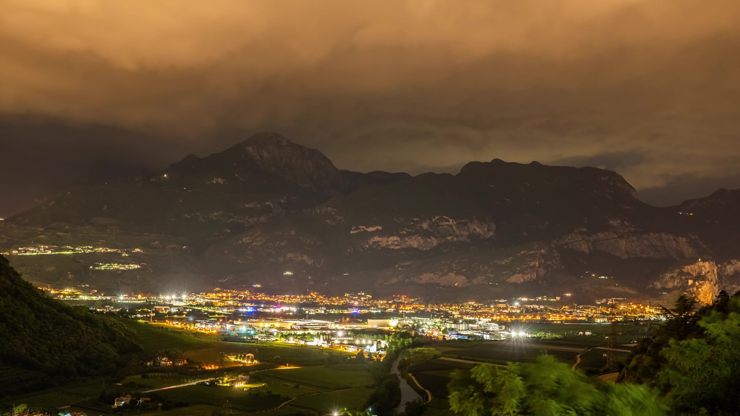 Timelapse of the city under a mountain at night