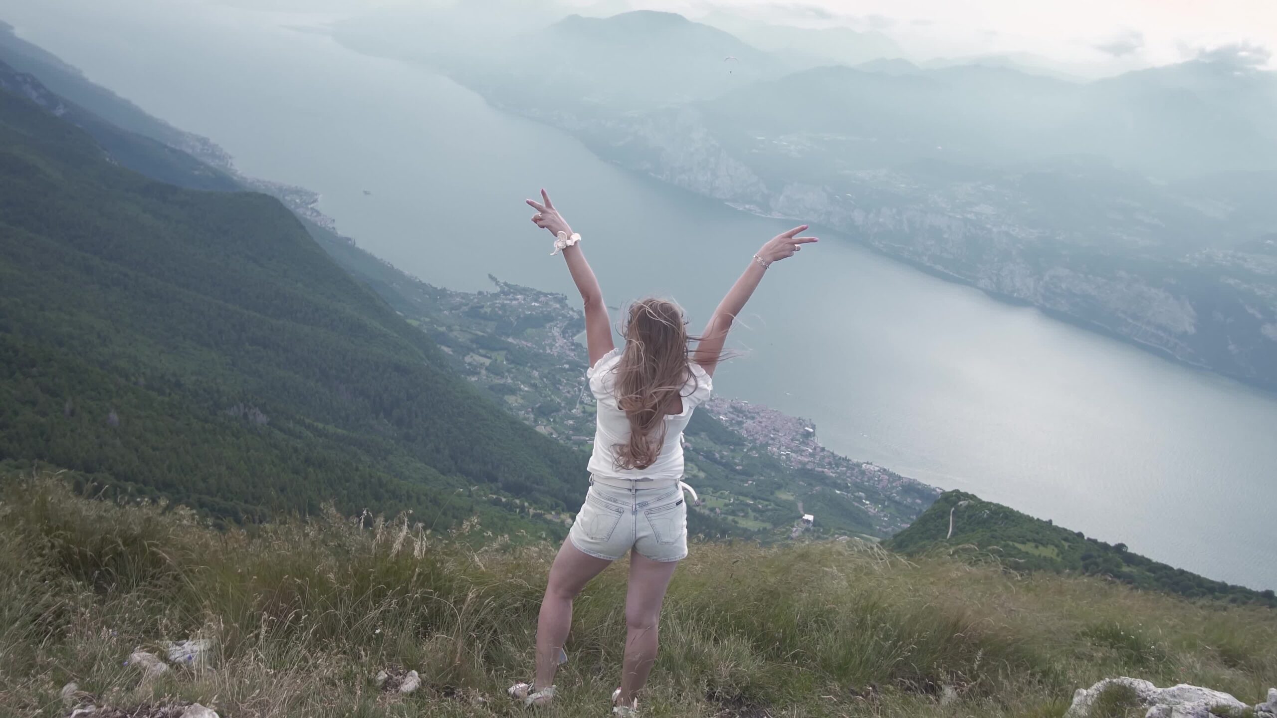 Woman blowing in the wind above Lake Garda mountains