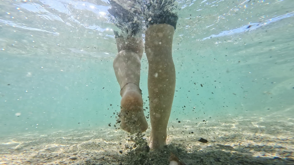 Gambe della donna che cammina in acqua