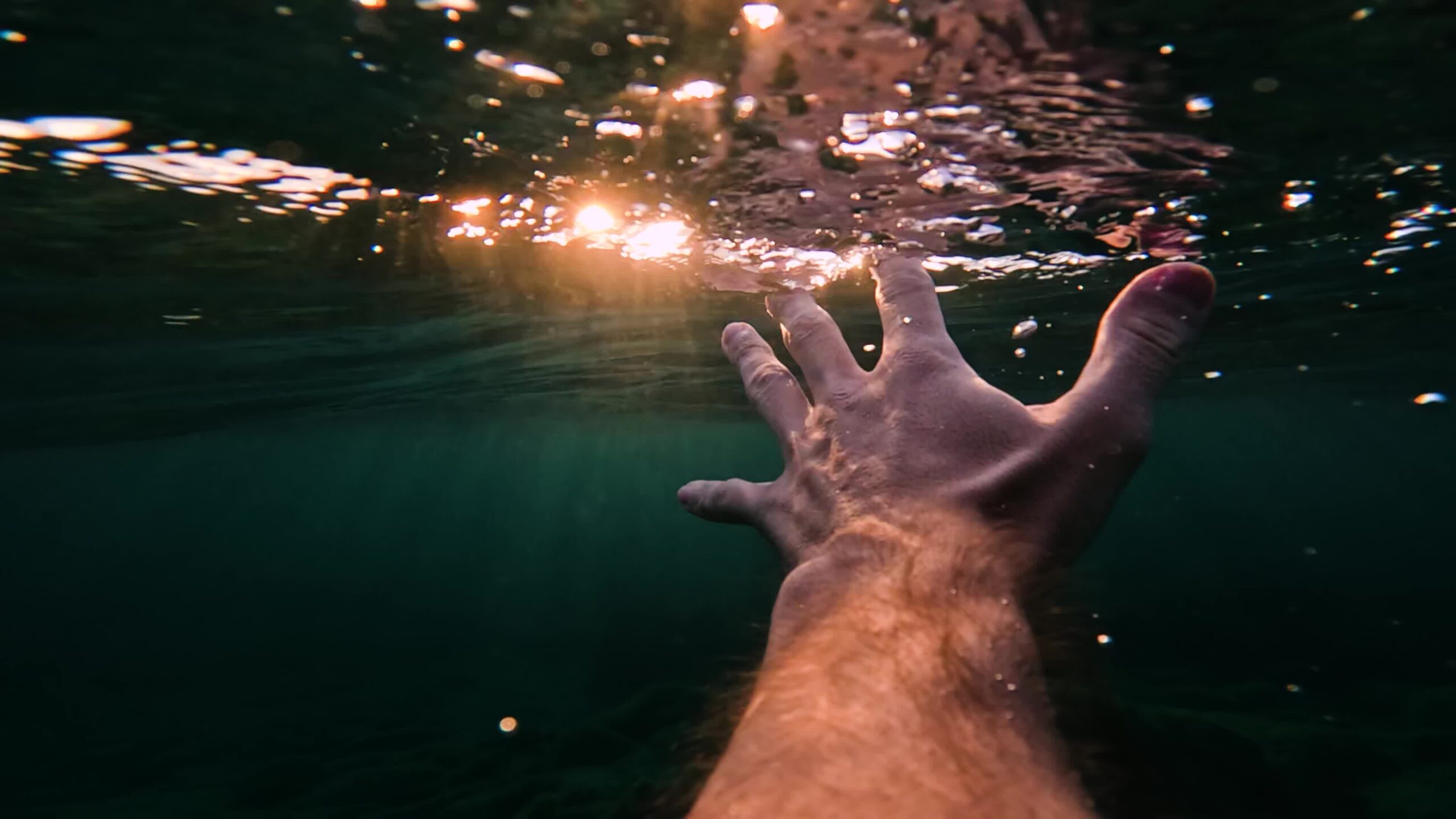 Hand under water illuminated by rays of light