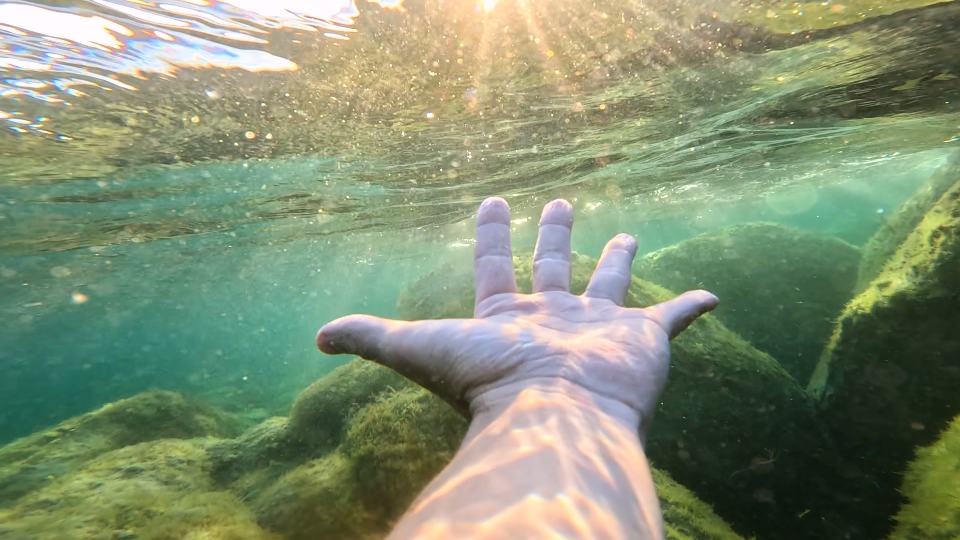 Palmo della mano sott’acqua illuminato dalla luce
