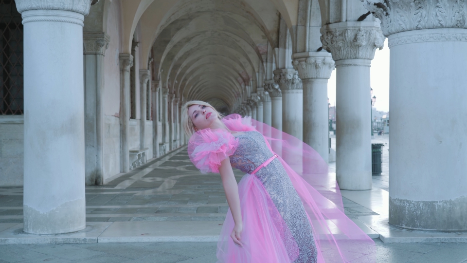 Donna in abito elegante rosa davanti archi veneziani