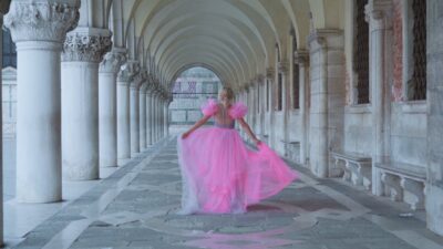 Modella in abito rosa cammina sotto portici