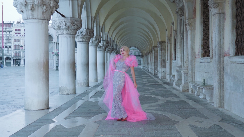 Model in pink poses under Venetian arches