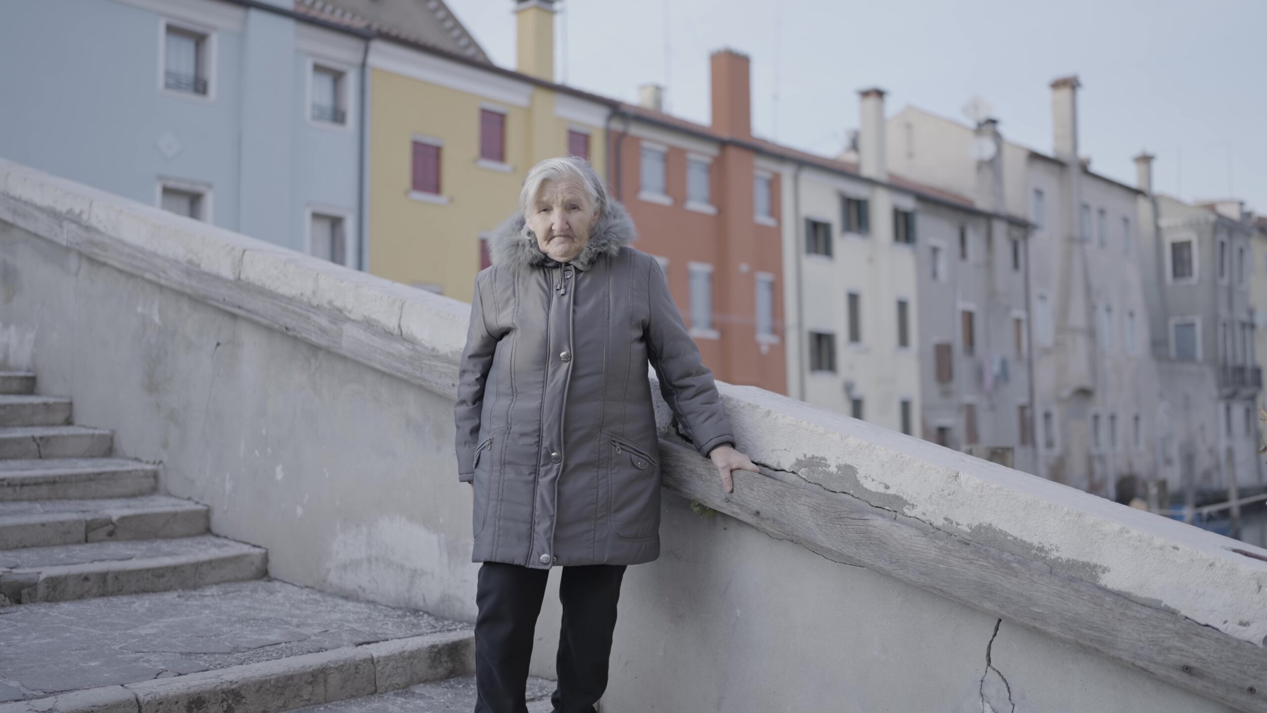 Una donna anziana è in piedi su un ponte