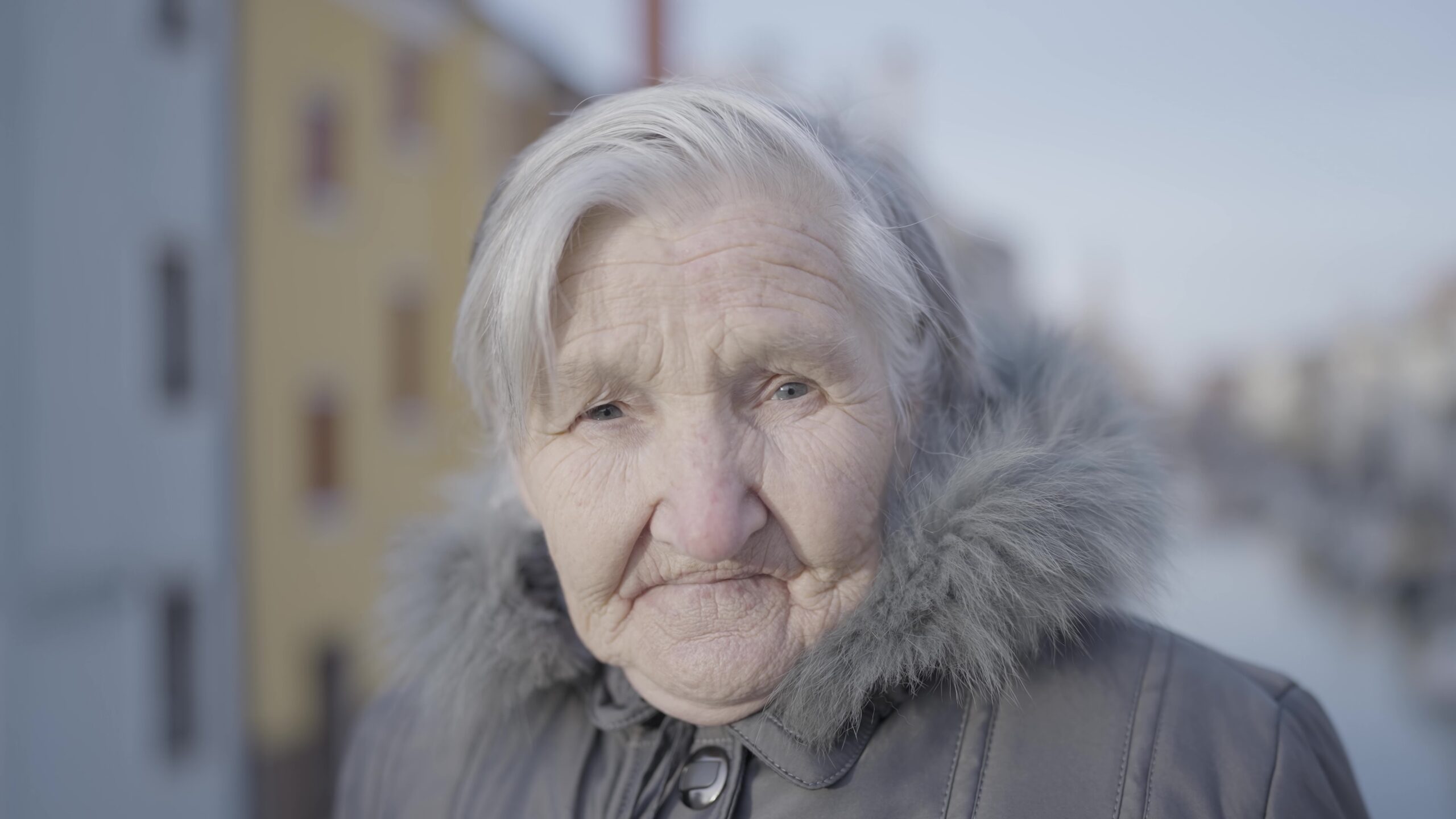 Elderly woman happy in fur coat, smiling under sky with wrinkles