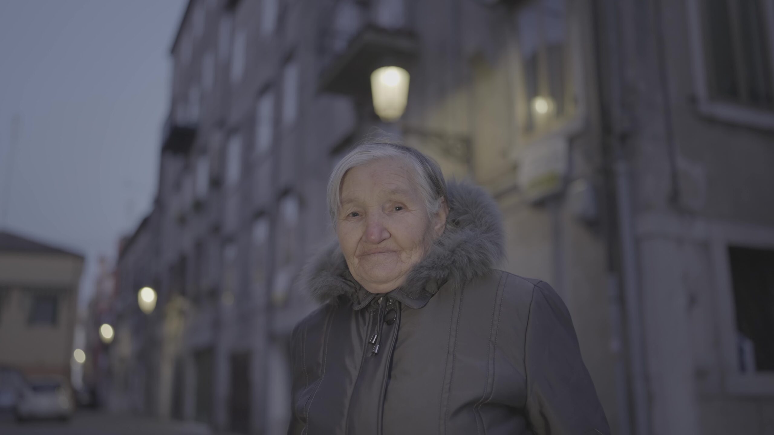 Elderly woman in a city street at night