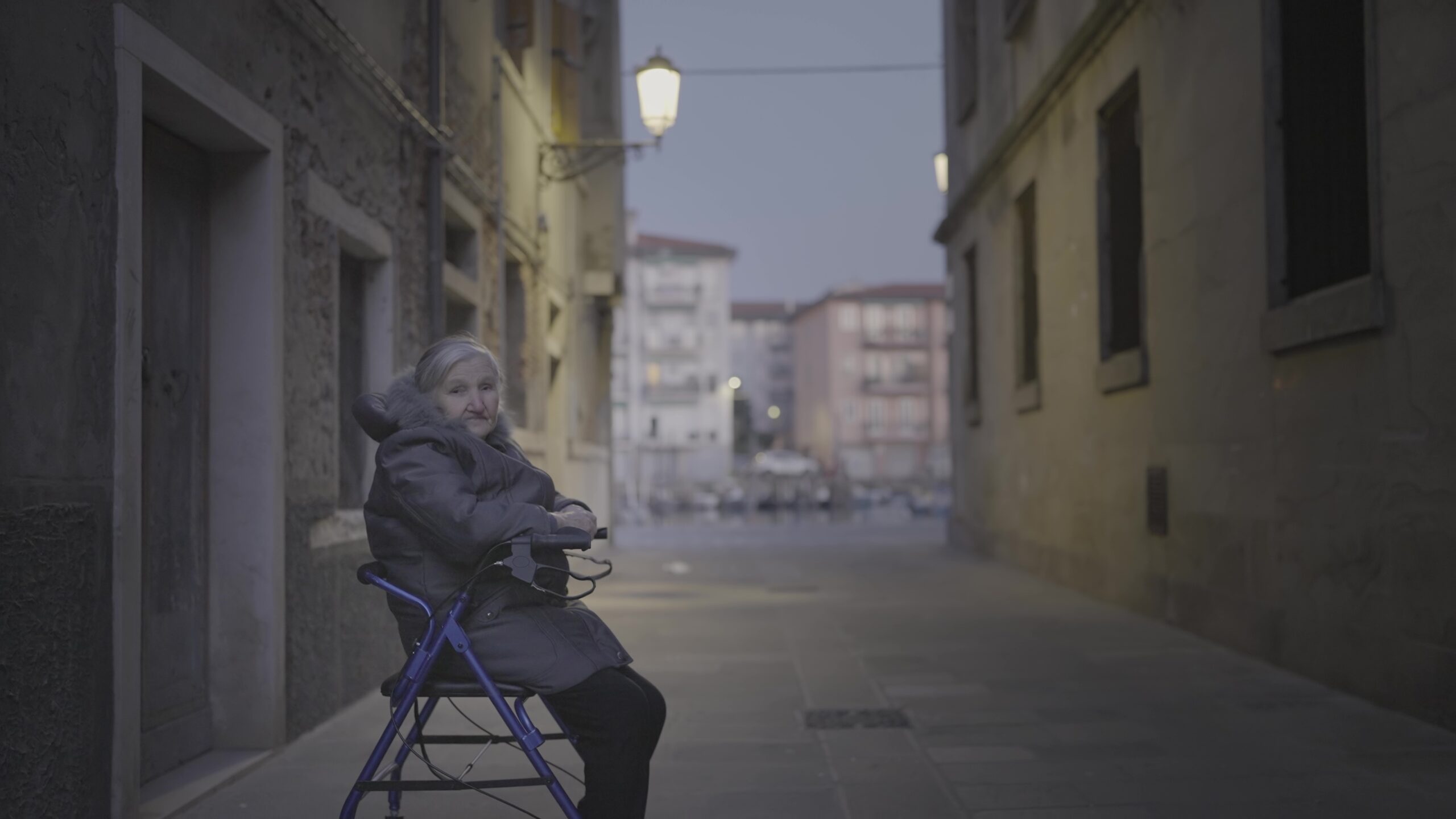 an elderly woman is sitting on a walker on a city street