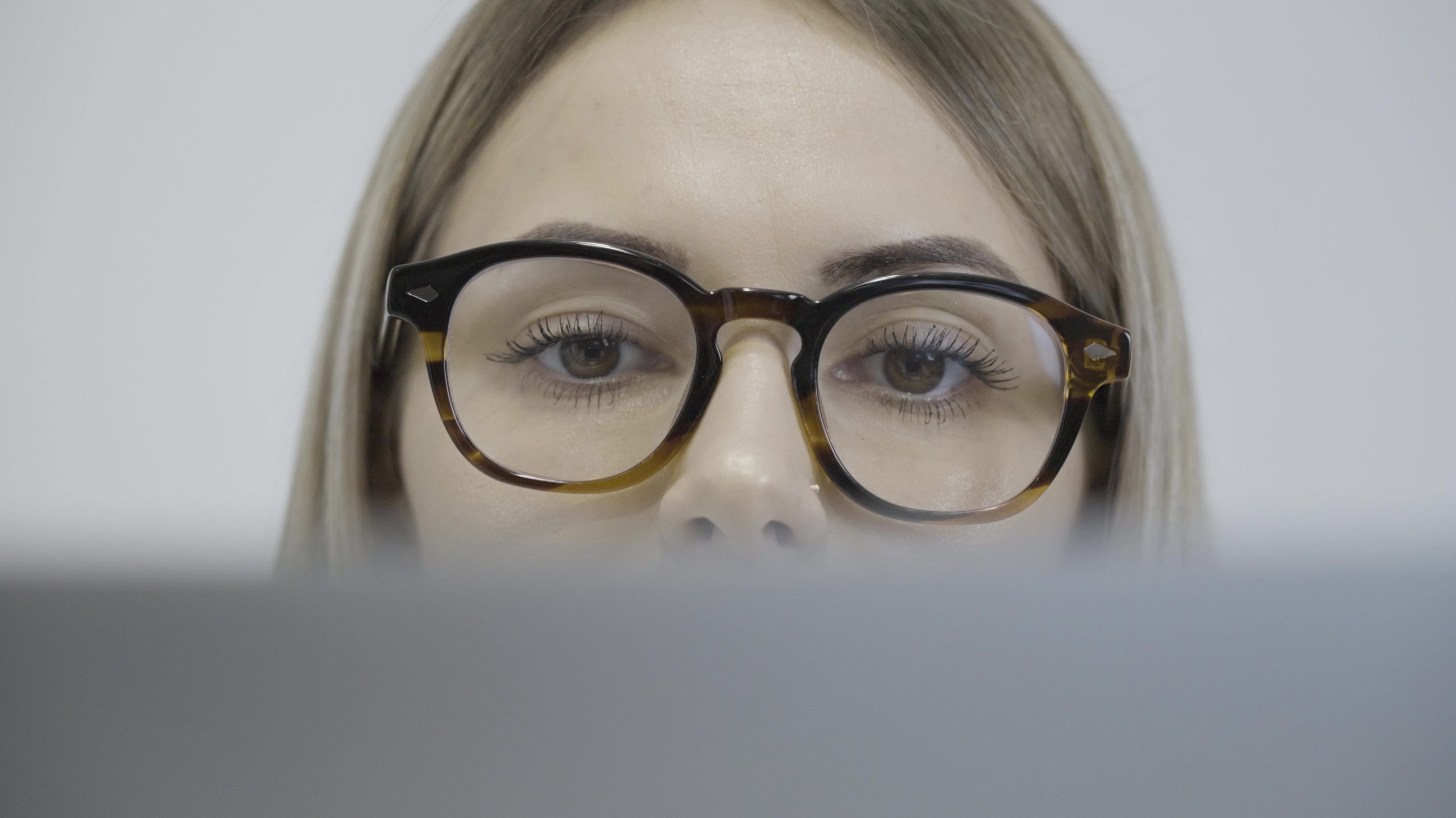 Una donna con gli occhiali che guarda lo schermo del laptop