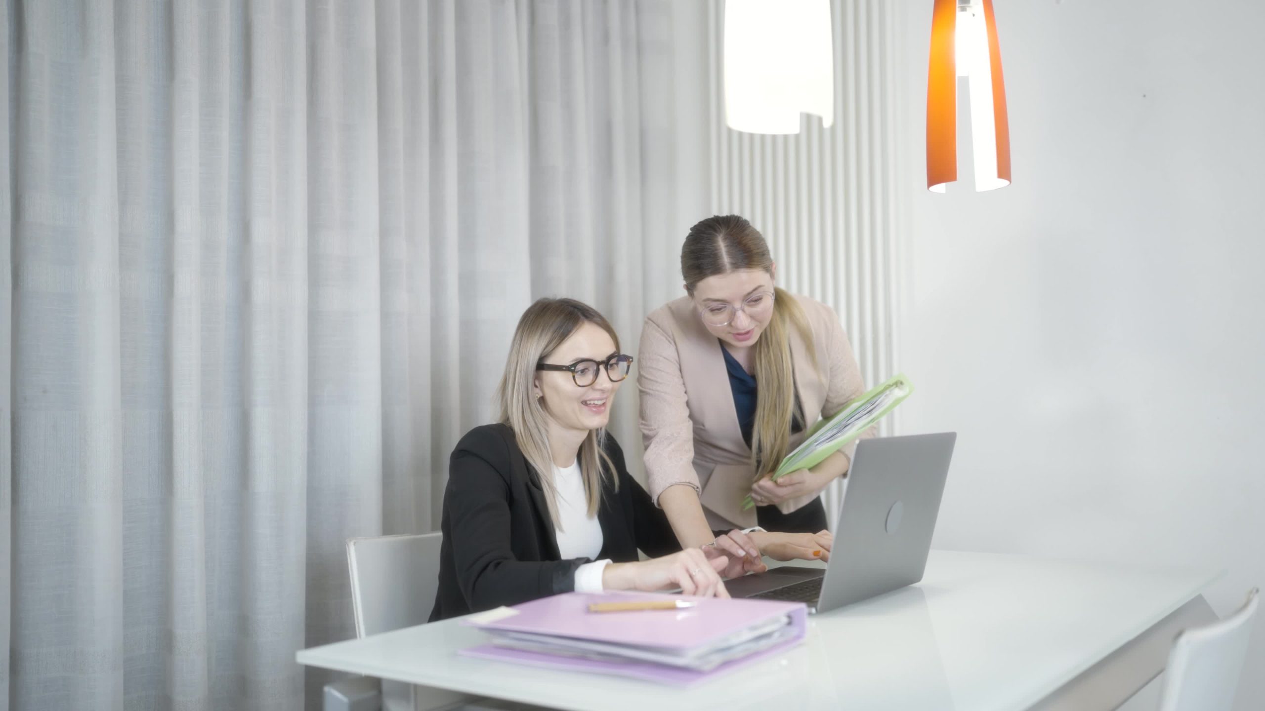 Due donne ridono davanti al computer in ufficio