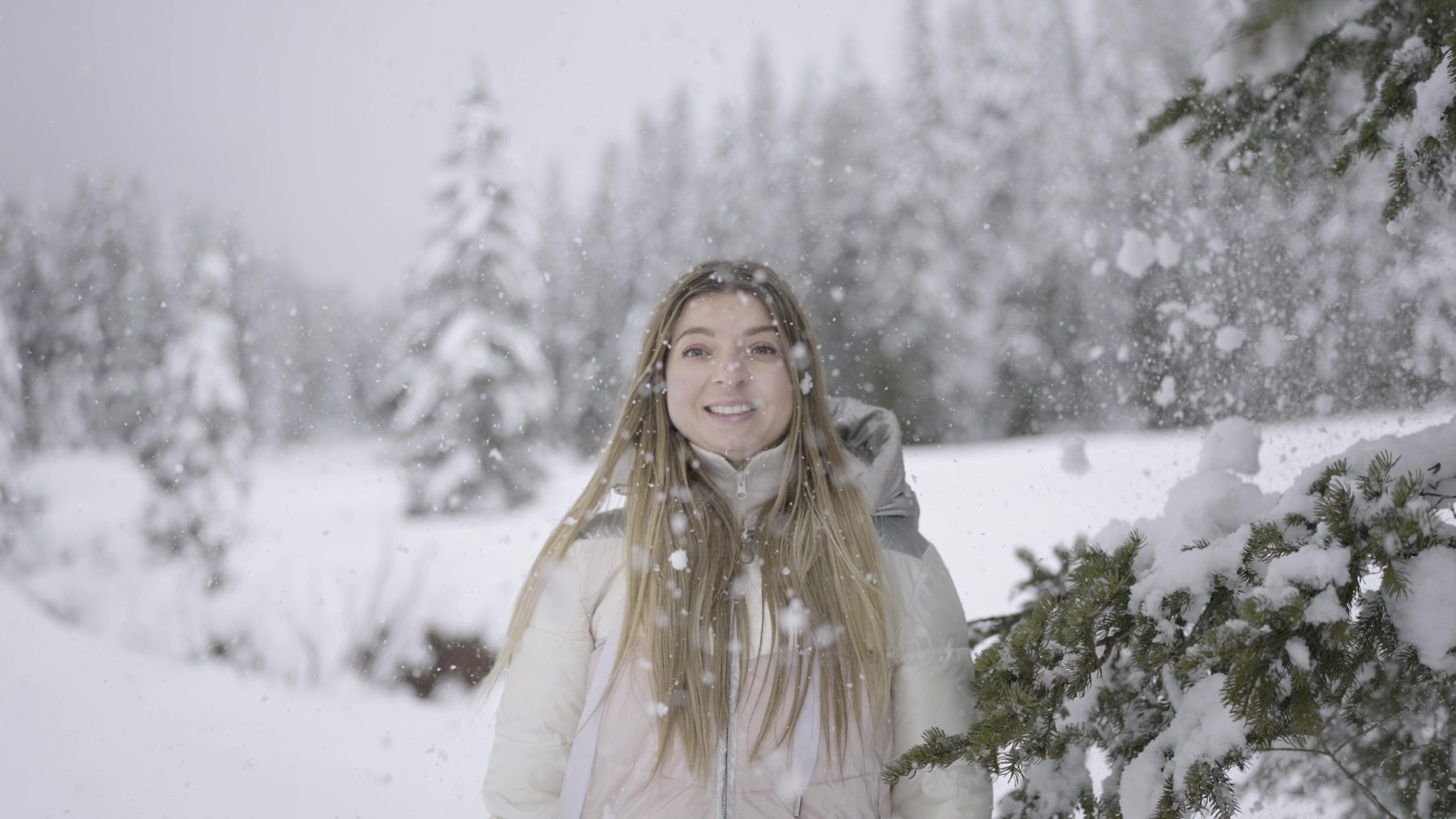 Neve cade sulla donna felice vicino all’albero
