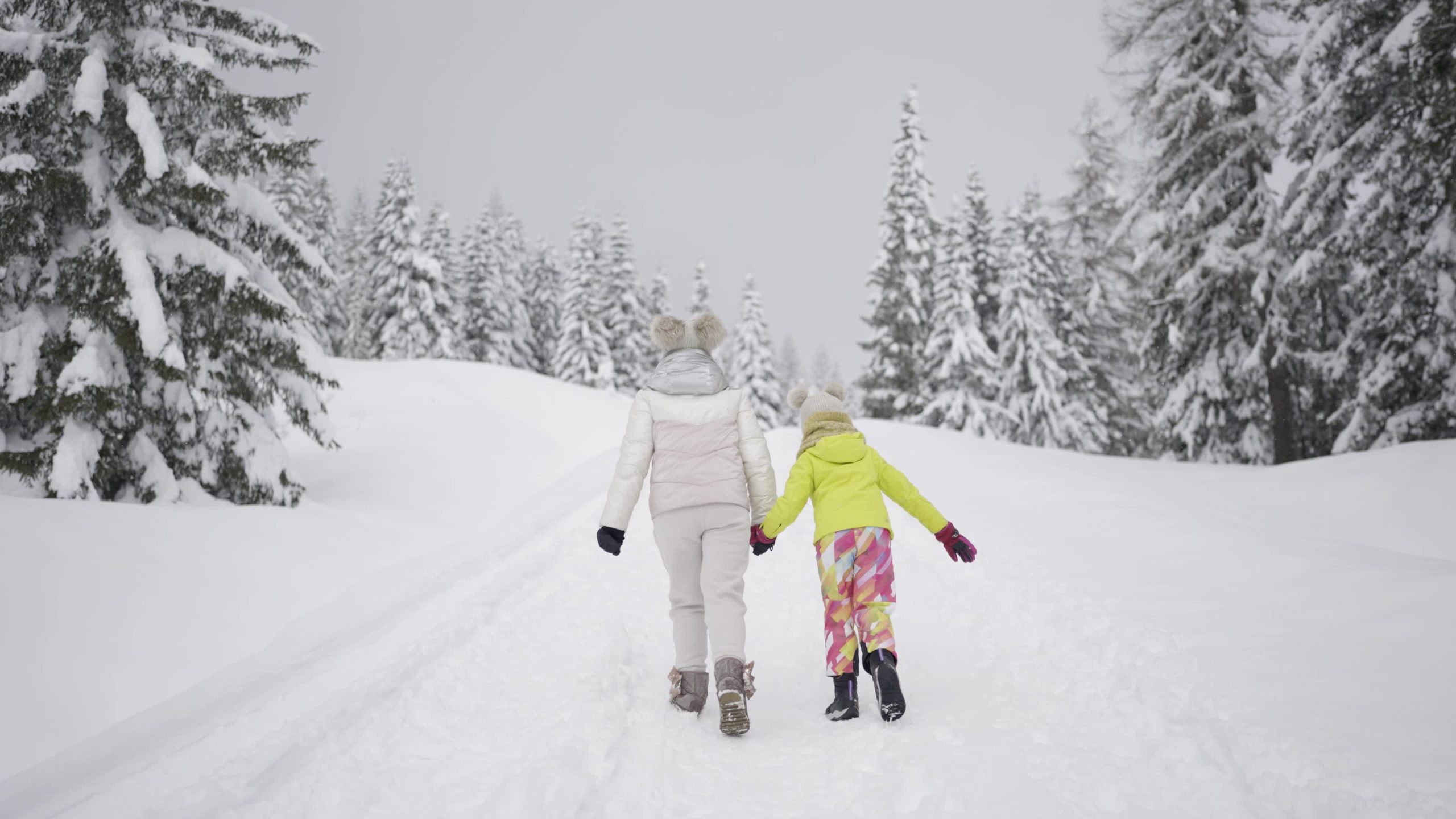 Mother and daughter walk in the snow in the forest