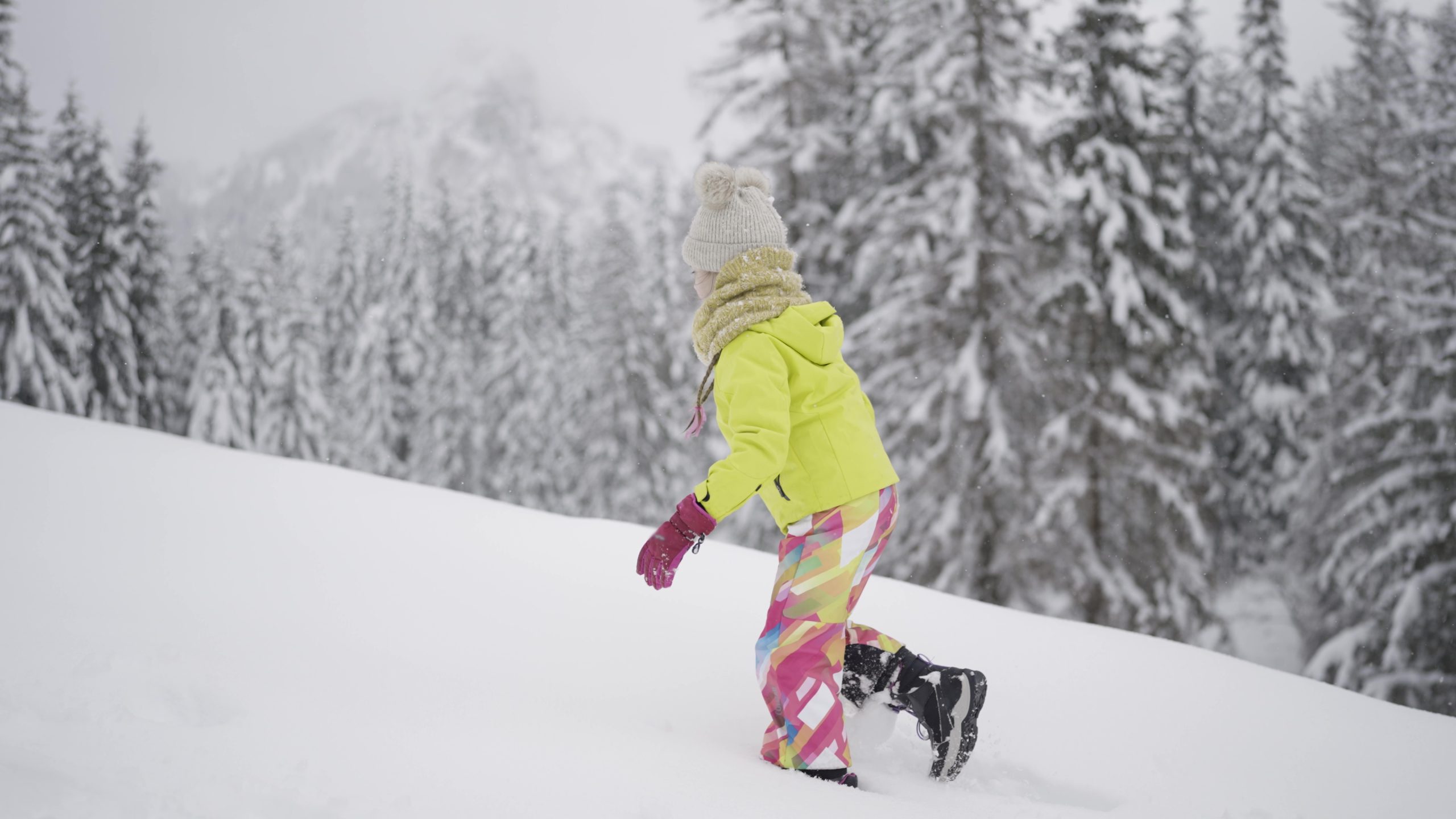 Little girl walks in the snow in the mountains