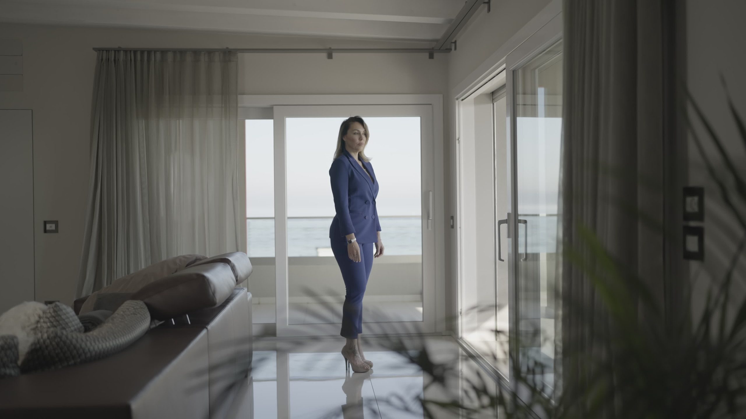 Donna seria con tacchi guarda nella finestra di casa