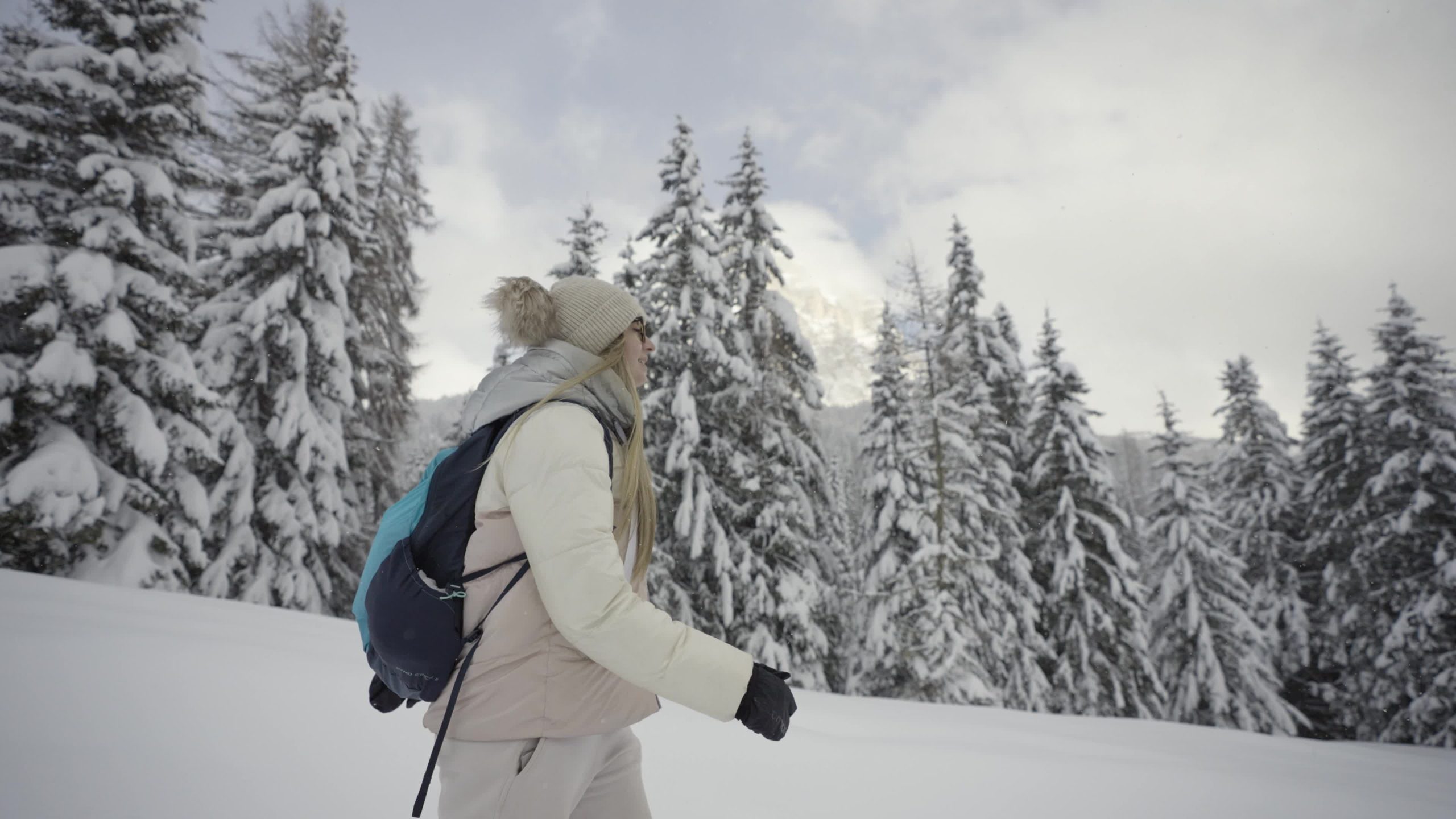 Donna con zaino cammina in montagna con la neve