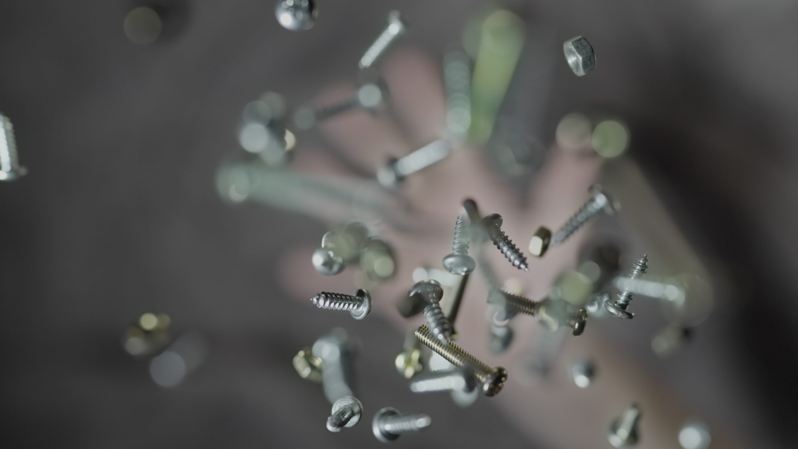 Steel screws are thrown upwards in slow motion