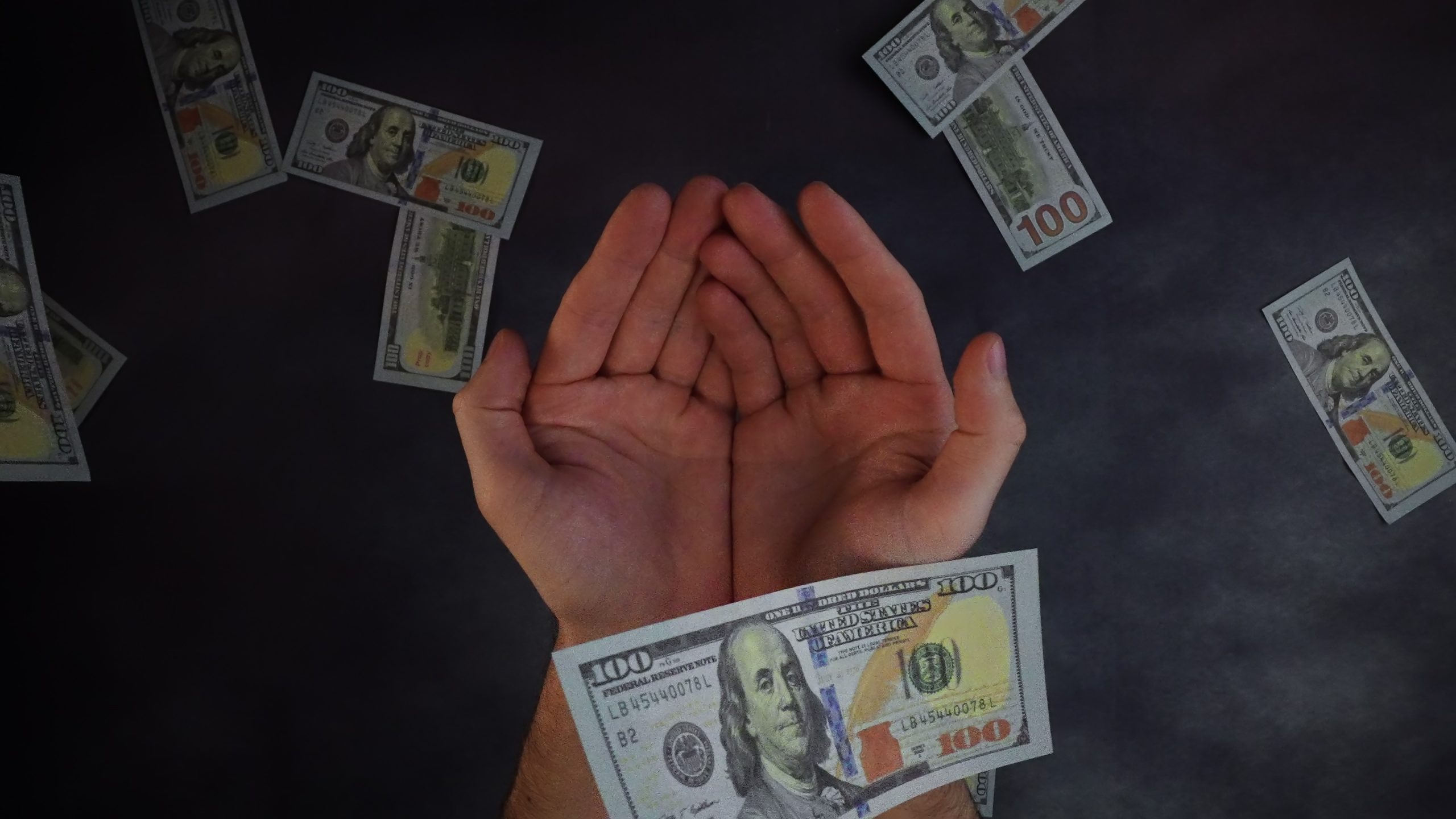 Banknotes fall from above and open palms