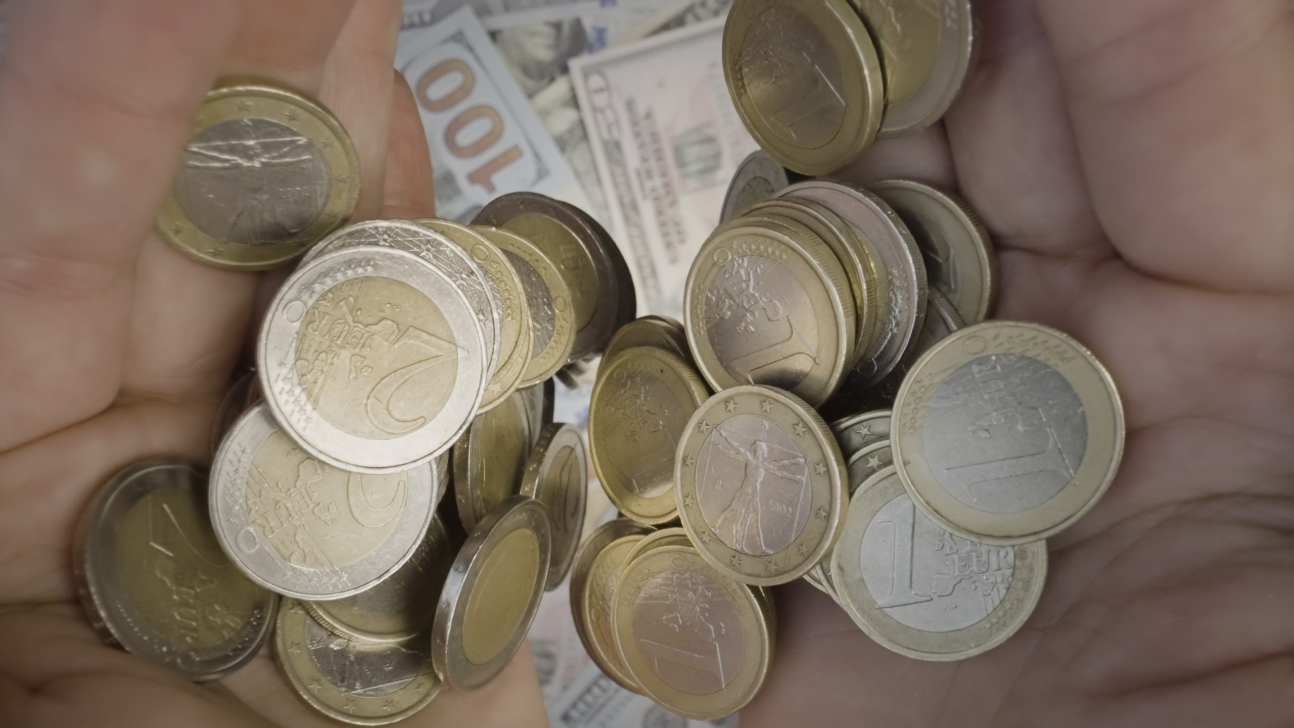 Coins fall from hands onto banknotes