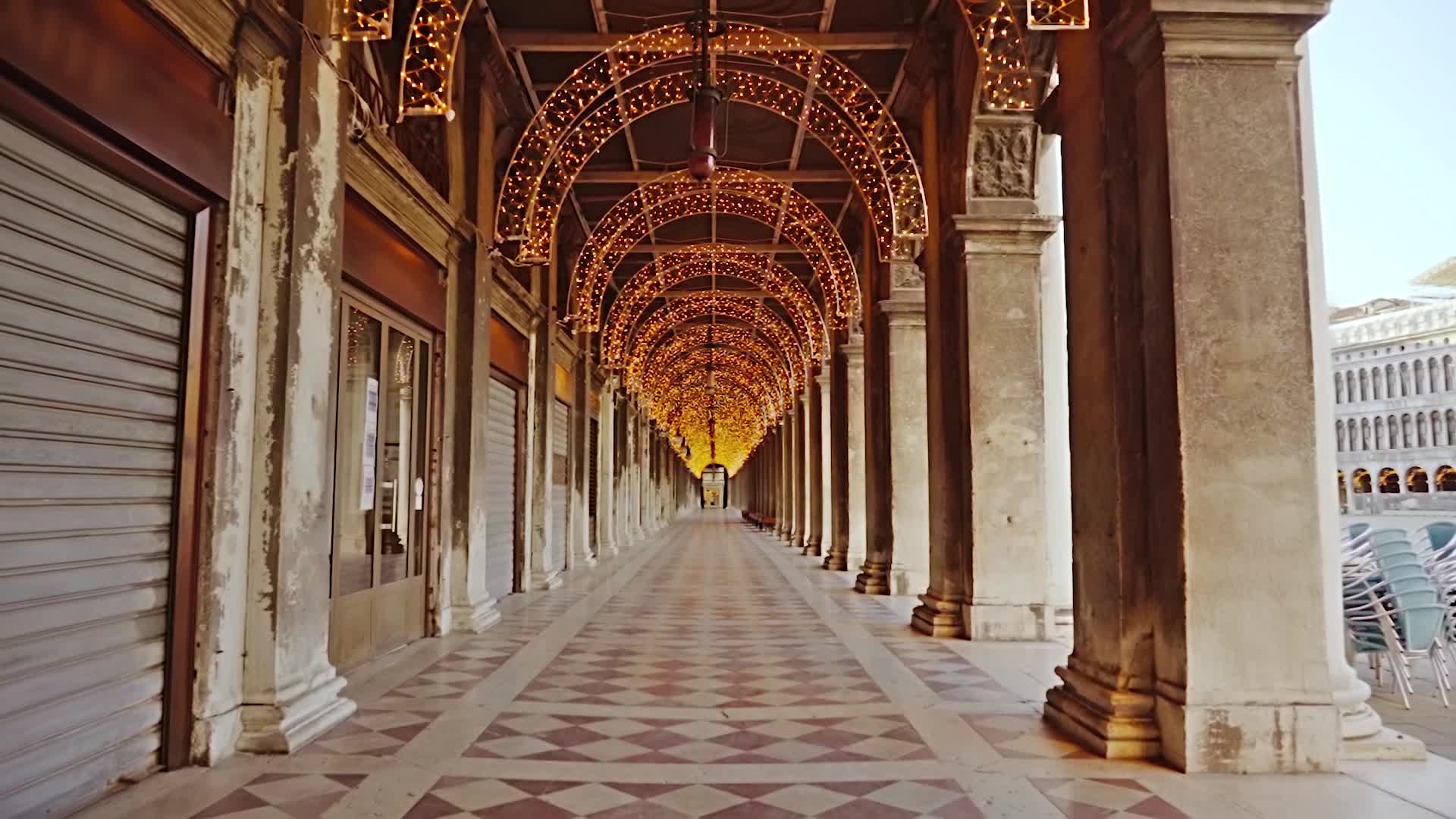 Movement between closed shops in the arched passage illuminated by decorative lights