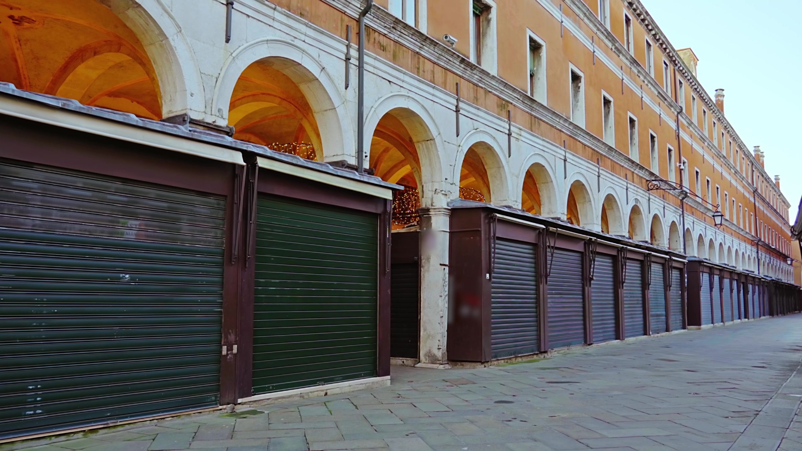 Piccoli negozi chiusi con serrande scure in edificio antico