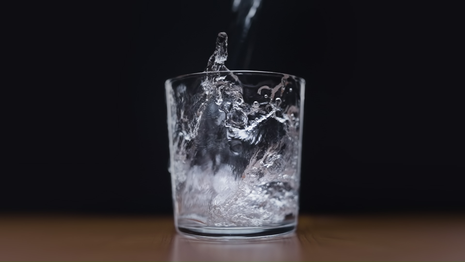 Water poured into glass on black background