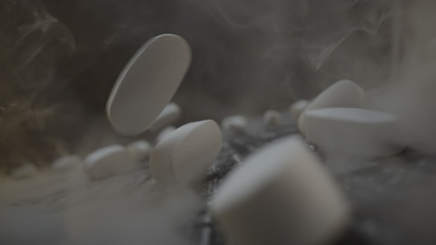 Pillole bianche che cadono nel fumo