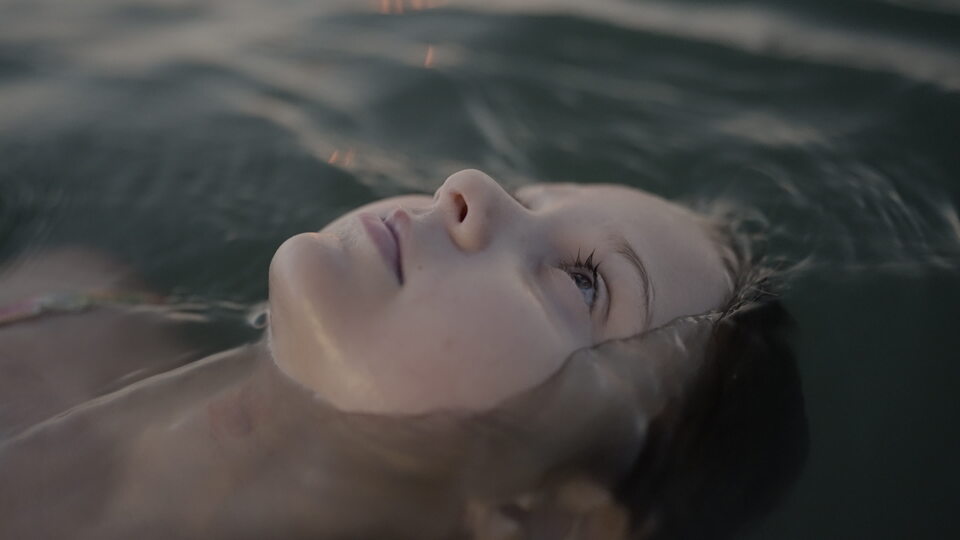 Ragazza che fluttua tranquillamente nell’acqua