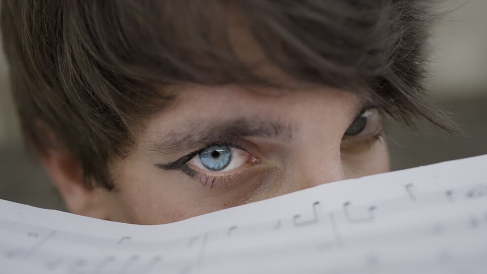 Primo piano dello sguardo intenso di un uomo sopra spartiti musicali