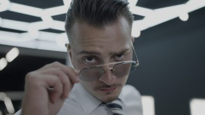 Confident man adjusting sunglasses with intense gaze