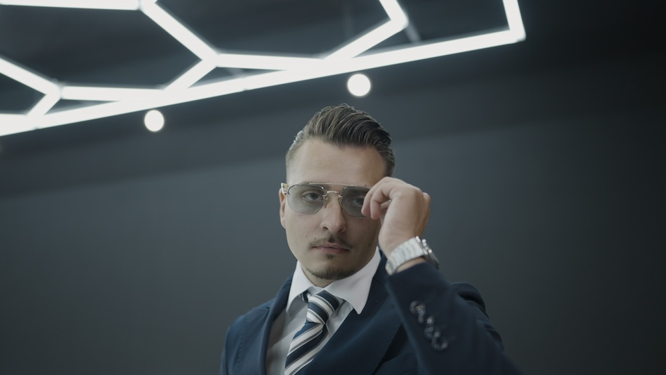 Confident man adjusting sunglasses in a sleek suit
