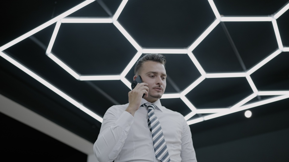 Uomo d’affari al telefono sotto illuminazione futuristica