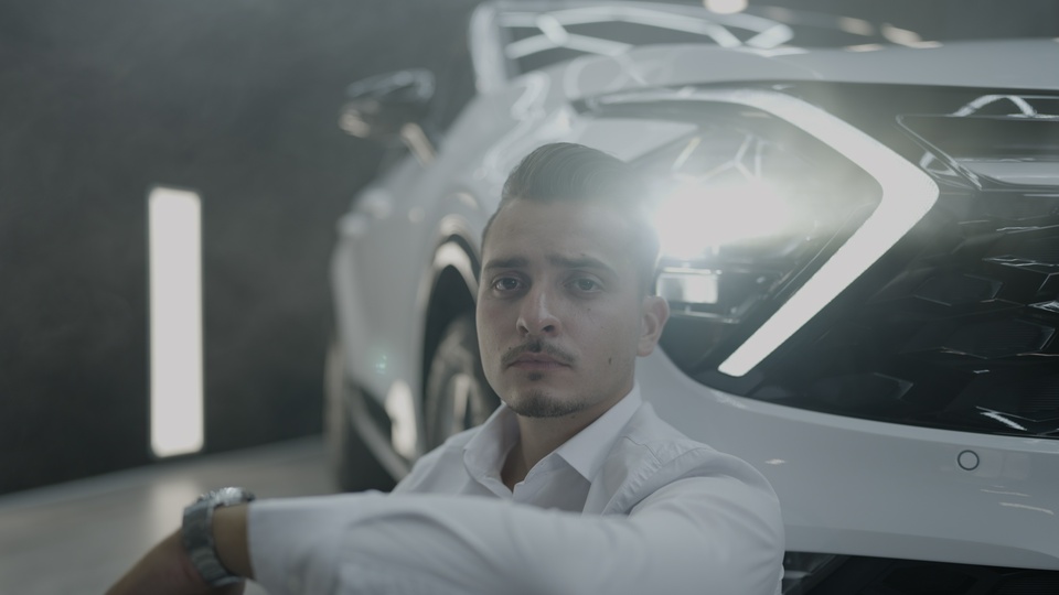 Uomo d’affari seduto pensieroso accanto al faro dell’auto