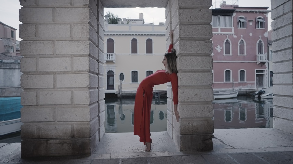 Donna elegante in rosso che posa vicino a un canale veneziano