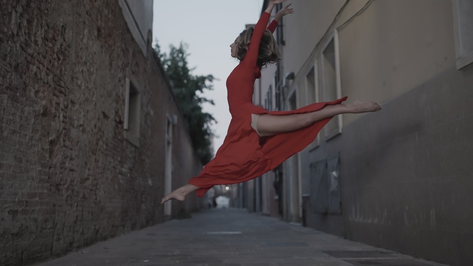 Dancer in Red Leaping Gracefully in Alleyway