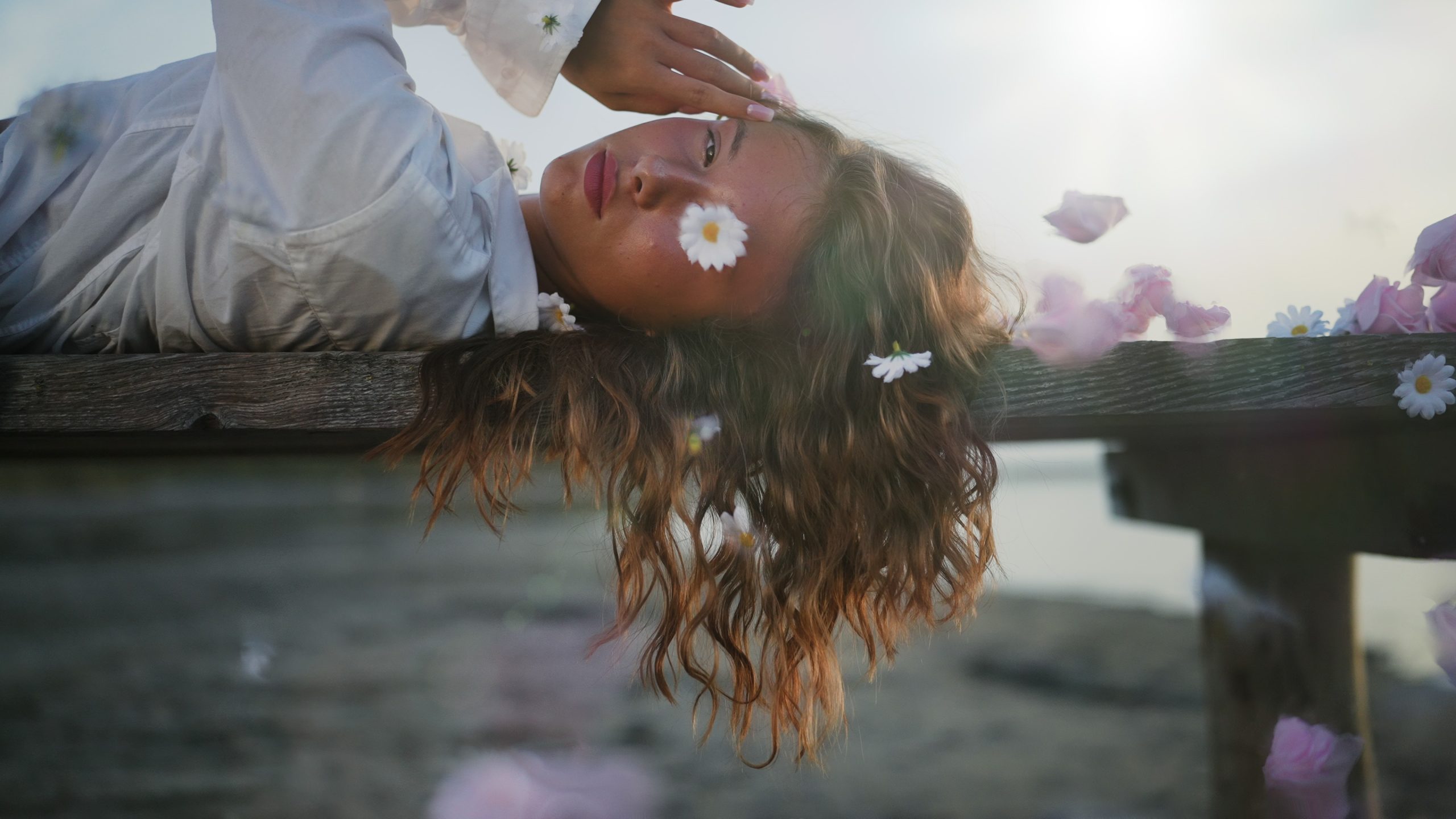Woman Lying on Pier with Falling Flowers