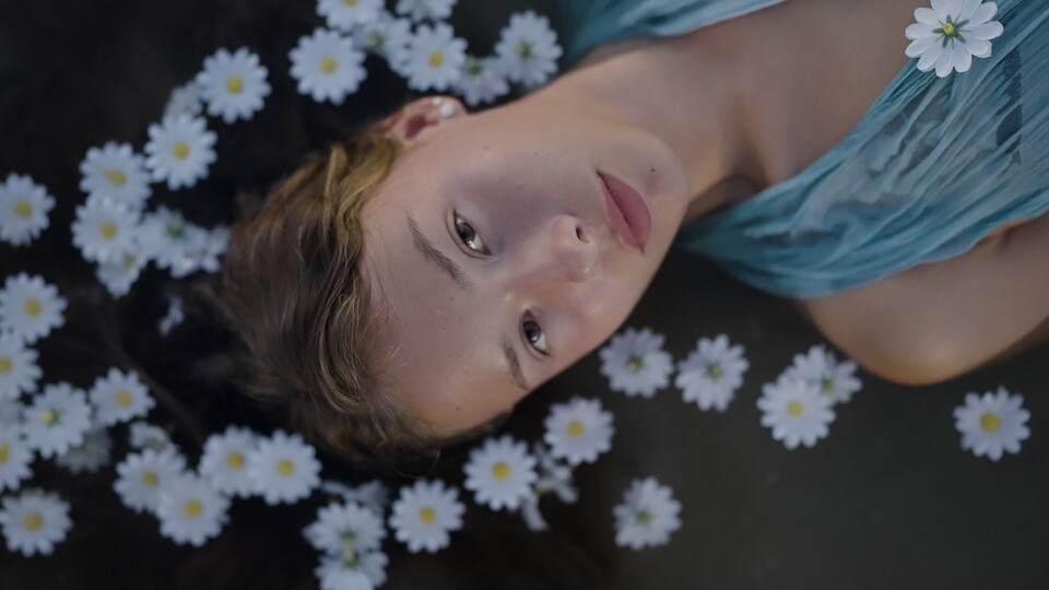 Woman Lying in Water Surrounded by Floating Daisies