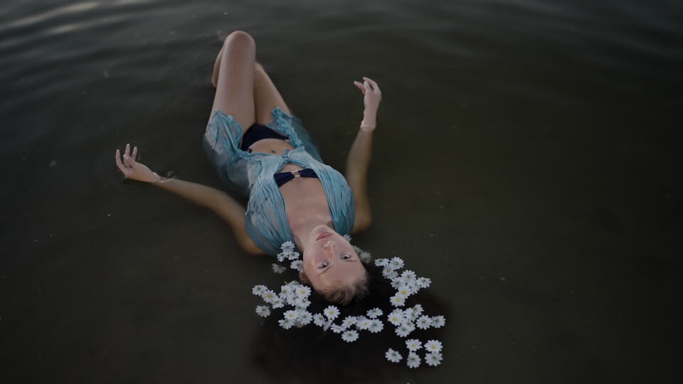 Woman Floating in Water with Daisies in Her Hair