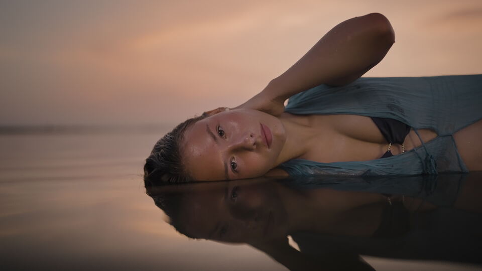 Woman Resting in Shallow Water at Sunset, Reflective Pose
