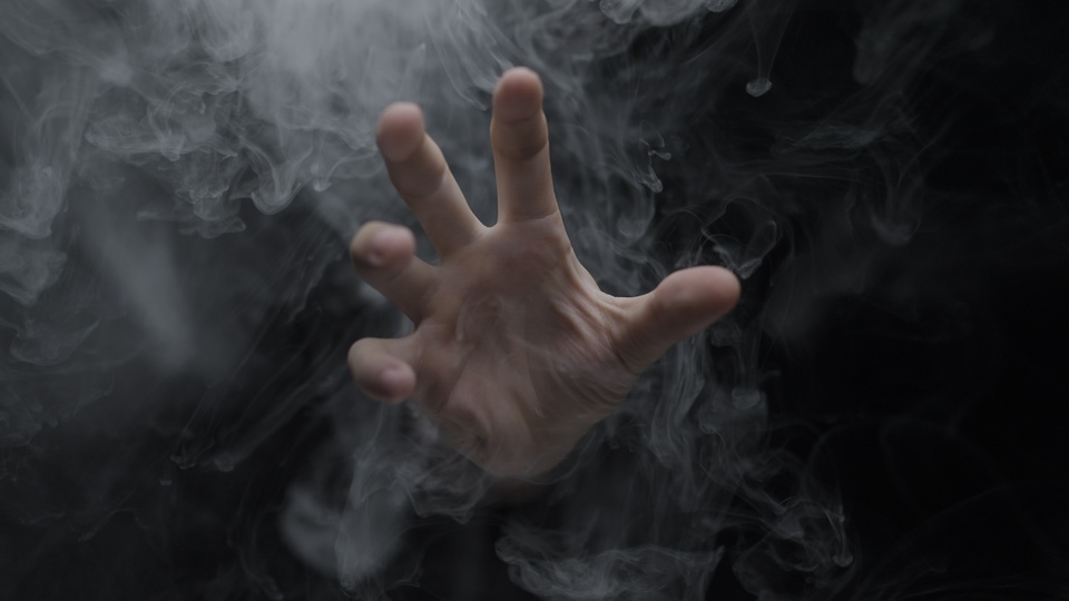 Hand emerging from swirling smoke